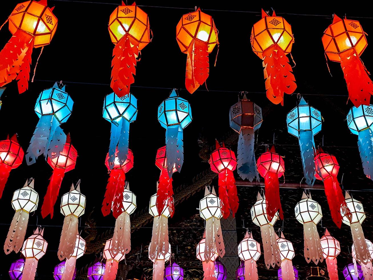 Farbenfroher Blick nach oben auf Laternen im thailändischen Lanna-Stil, die nachts beim Loy-Kratong-Festival vor dem Tempel hängen. foto