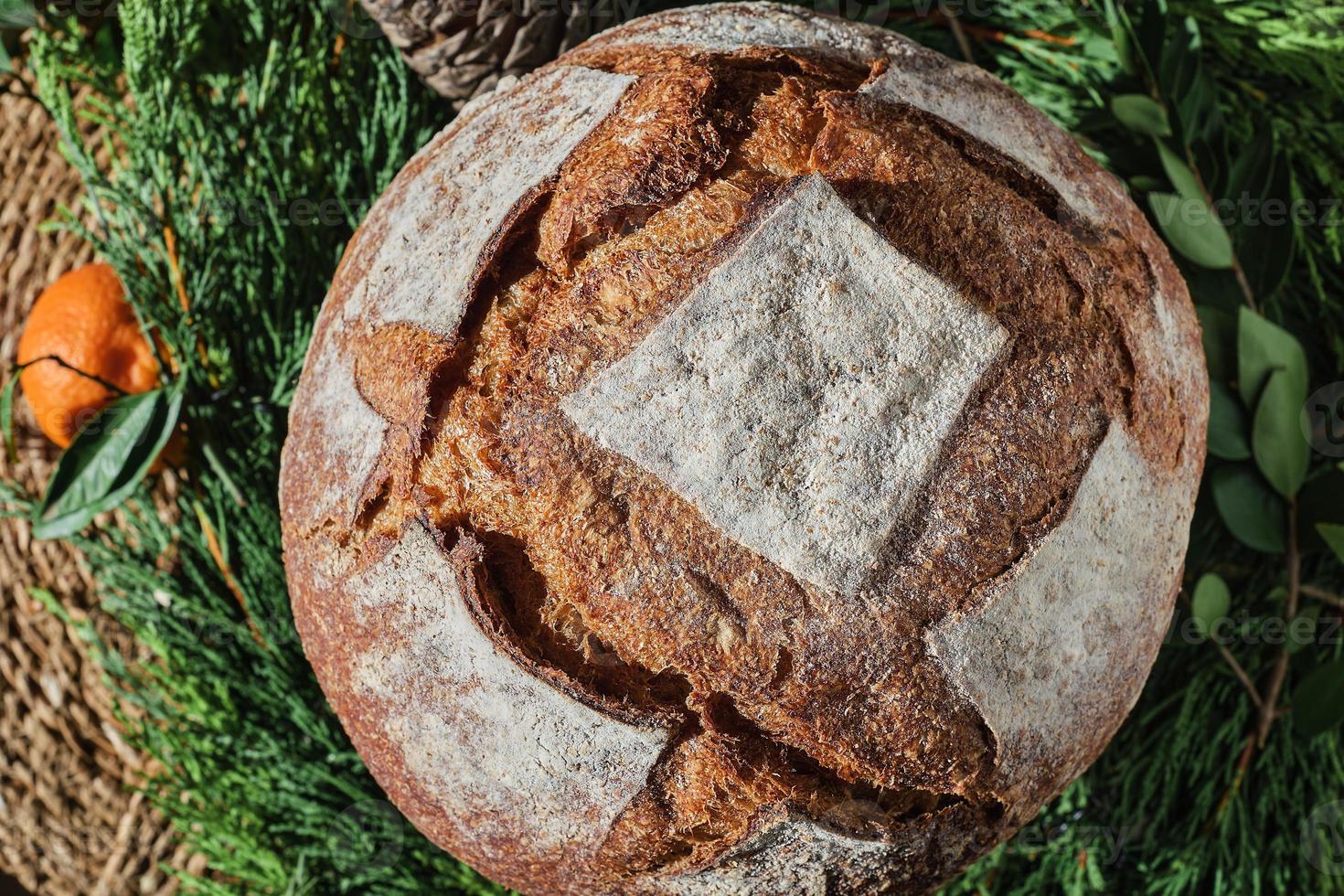 traditionelles rundes brot auf einem weihnachtskranz, draufsicht. Verkauf von handwerklichem Brot für die Neujahrsfeiertage foto