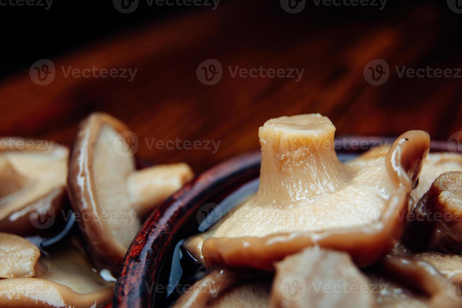 sehr leckere rustikal eingelegte Pilze in einem Tonbecher auf einem Holztisch. gesundes Essen . foto
