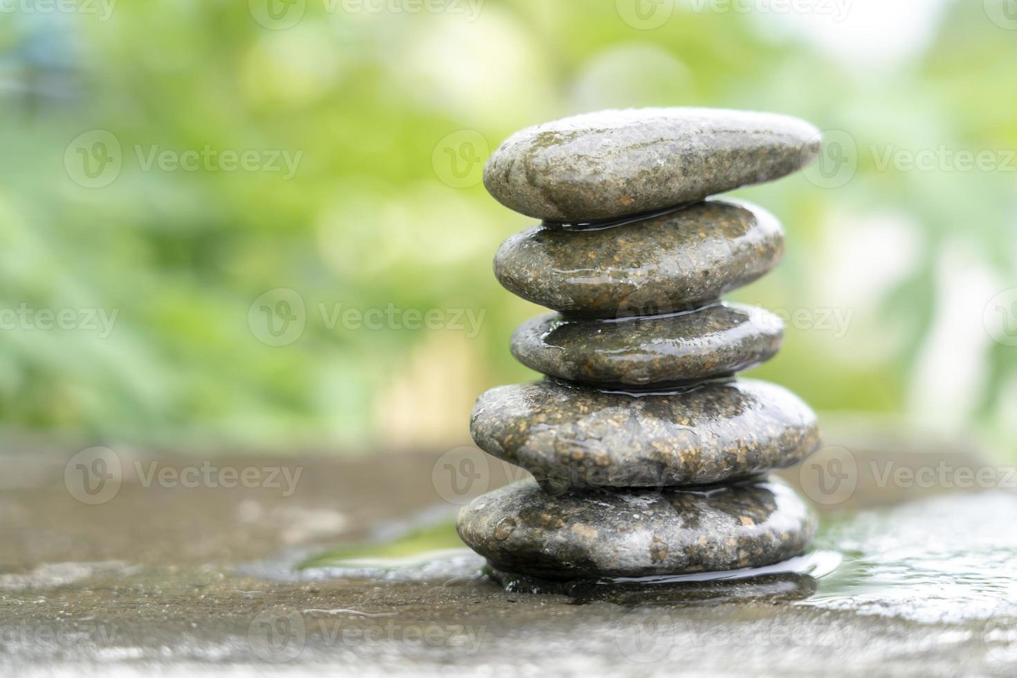 Meditationssteine mit Regentropfenwasser auf Zementboden auf grünem Naturhintergrund. Pyramidenkiesel freier Speicherplatz. Ruhe, Buddhismus-Symbol oder Aromatherapie-Set-Konzept. foto