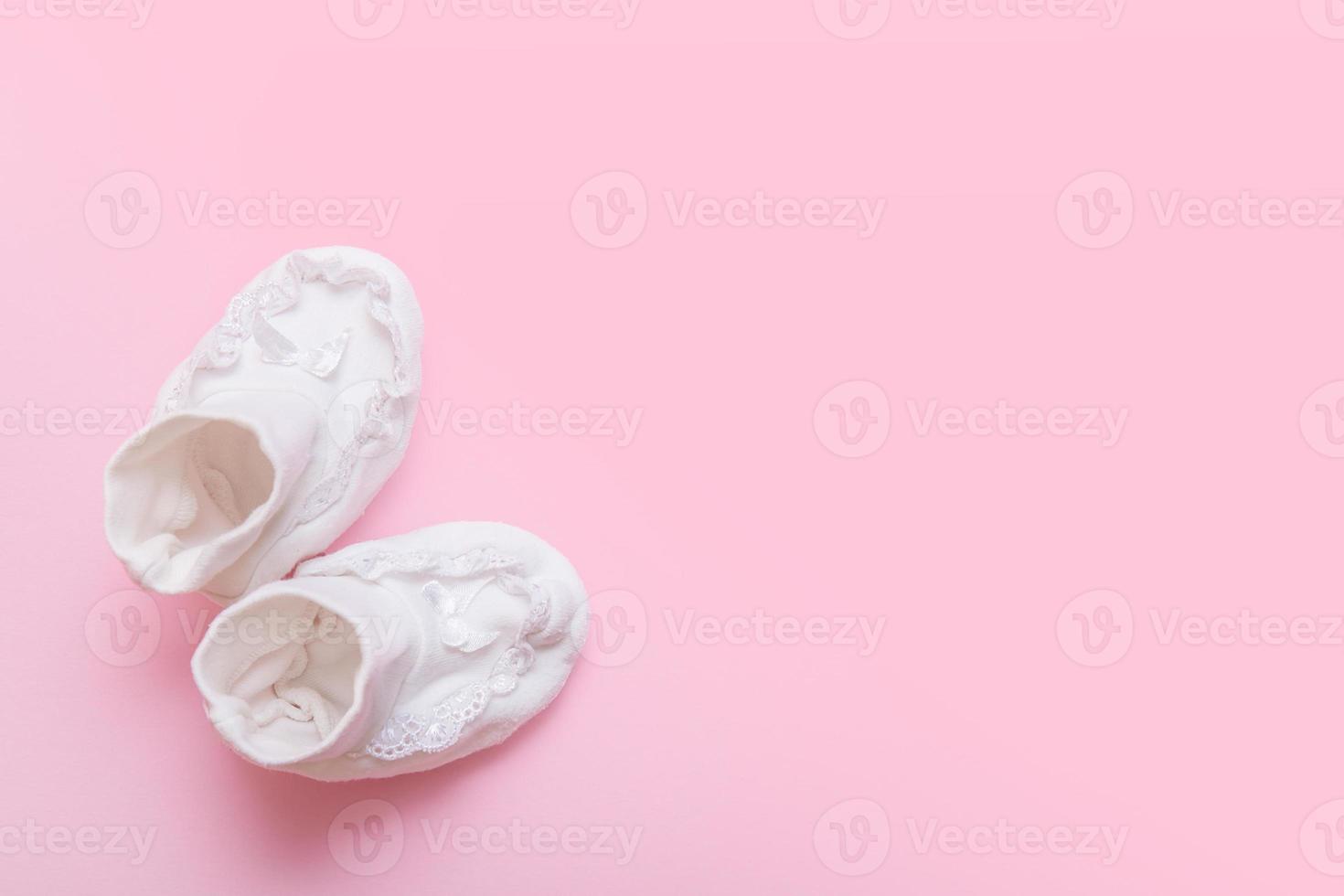 weiße booties für ein neugeborenes auf einem rosa hintergrund mit kopienraum foto
