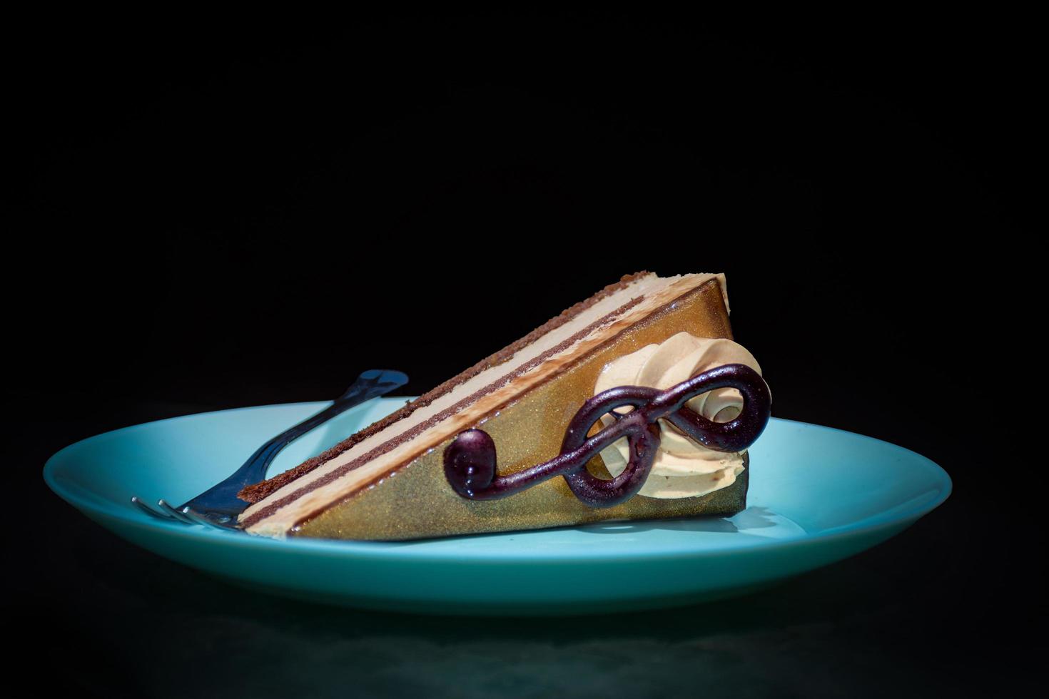 ein Stück Kuchen mit einer Geigentaste auf einem blauen Teller im Scheinwerferlicht foto