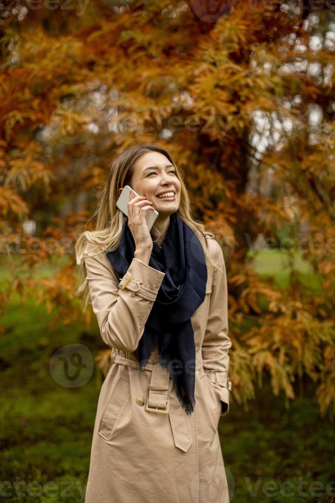 junge Frau mit Handy im Herbstpark foto