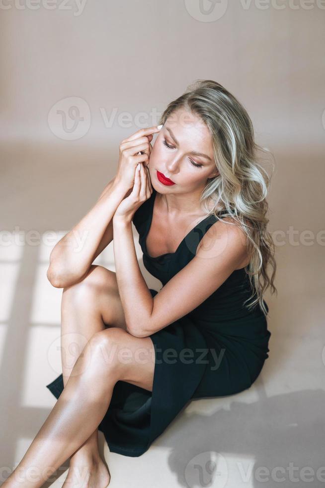 Porträt einer wunderschönen blonden jungen Frau mit hellem Make-up im Abendkleid auf beigem Hintergrund foto