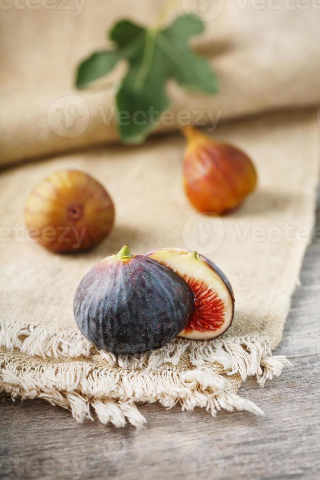 Reife Bio-Feigen auf dem Tisch. Gruppe von lila und grünen Feigen auf einem Bauernholztisch mit Sackleinen foto