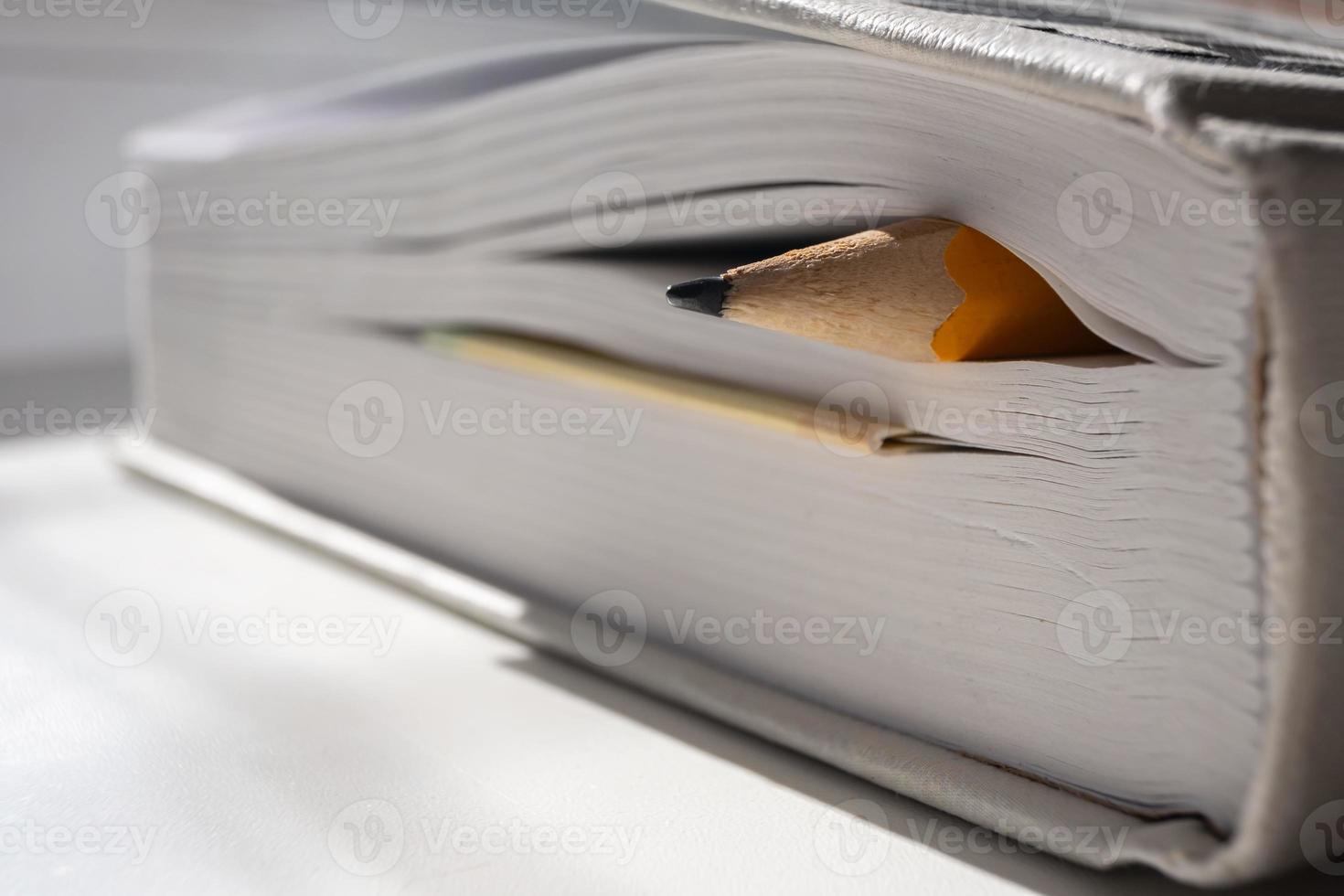 gespitzter Bleistift ist in den Seiten eines geschlossenen Buches. Bildungskonzept. foto