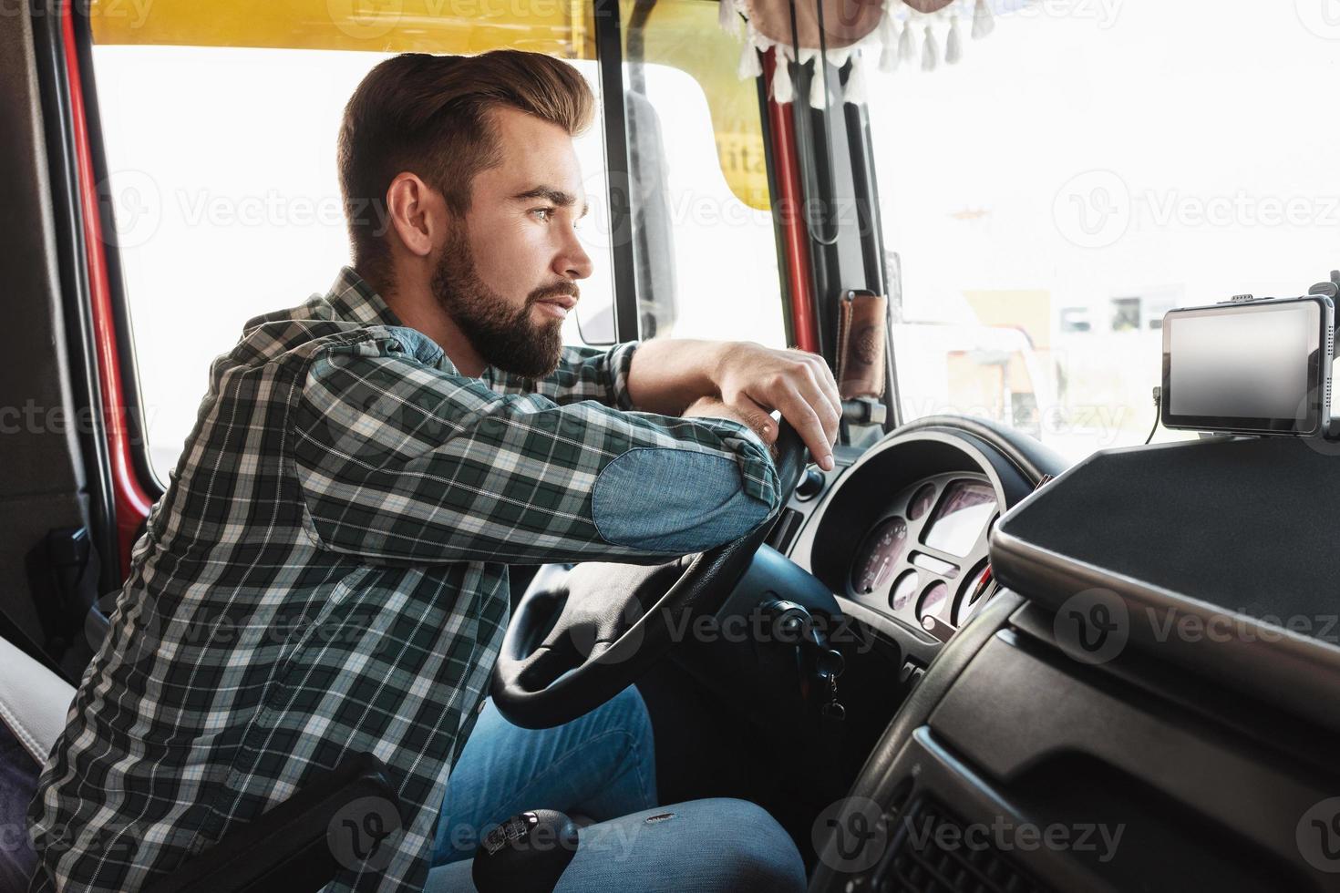 junger professioneller lkw-fahrer, der in seinem fahrzeug sitzt foto