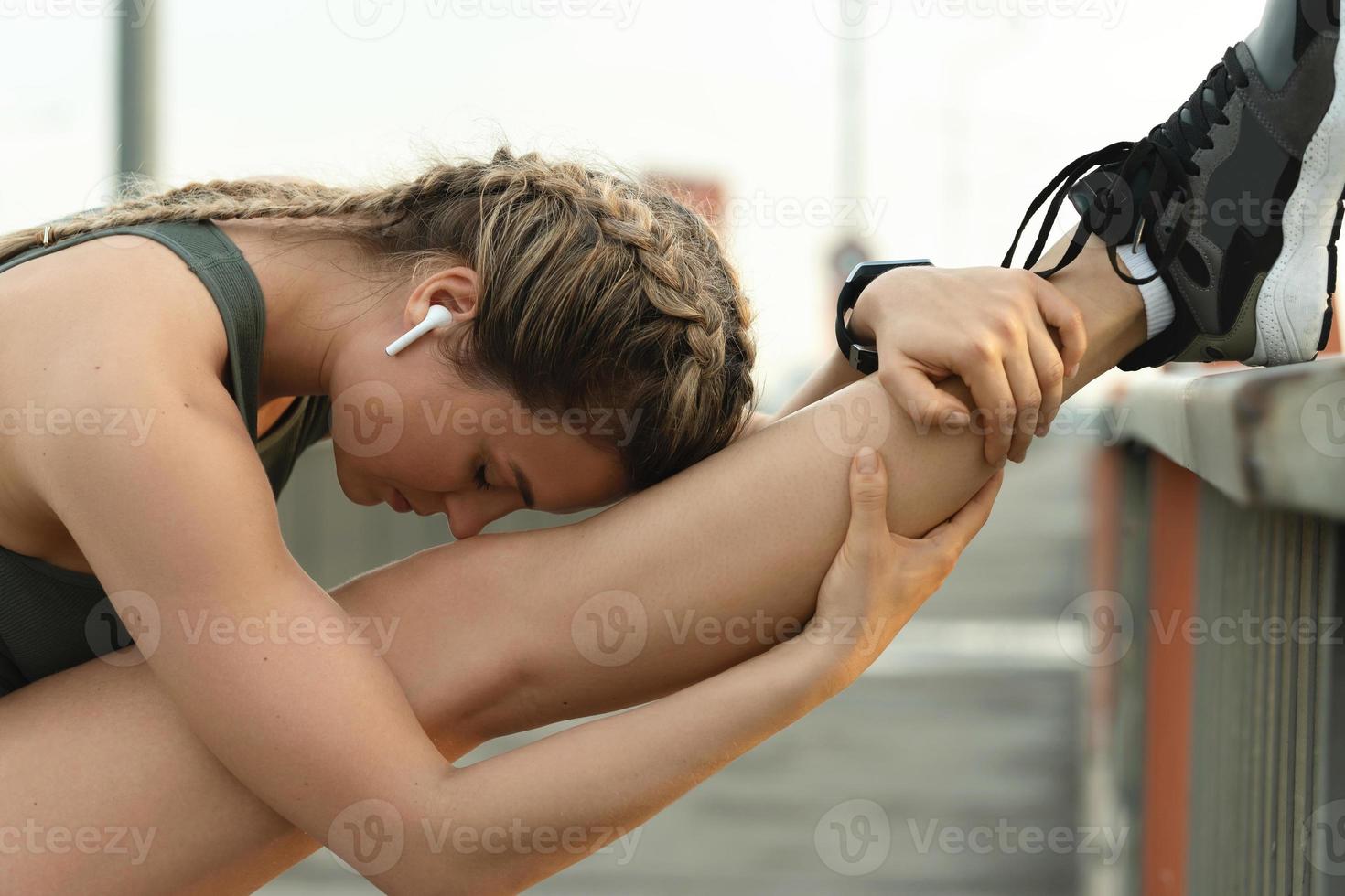 Sportliche Frau dehnt sich während des Fitnesstrainings auf einer Straße foto