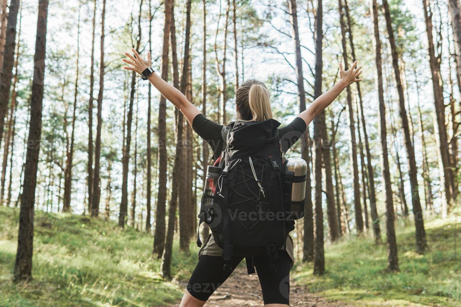 Wanderin mit großem Rucksack im grünen Wald foto