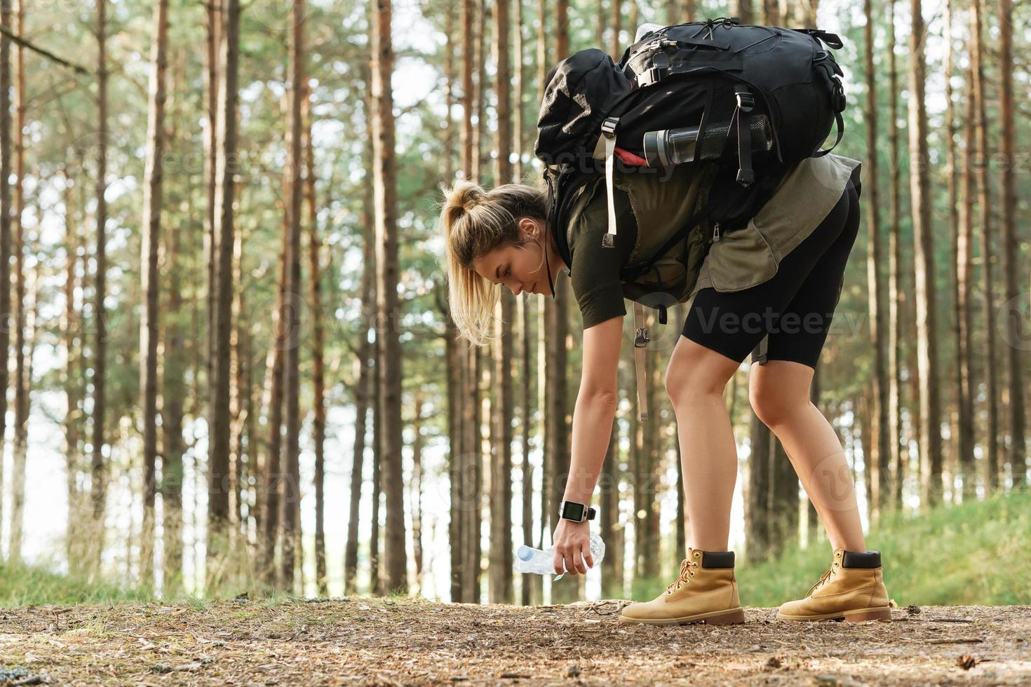 Wanderin sammelt Plastikmüll im grünen Wald foto