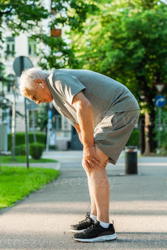 älterer mann, der während seines jogging-trainings unter knieschmerzen leidet foto