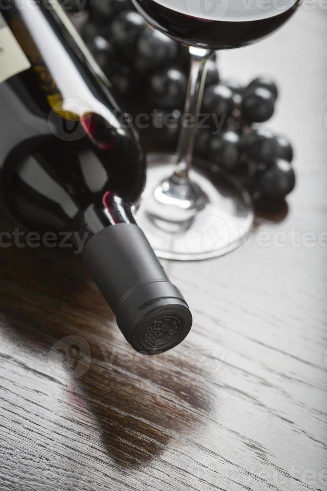 abstrakte Weinflasche, Glas und Trauben auf reflektierender Holzoberfläche foto