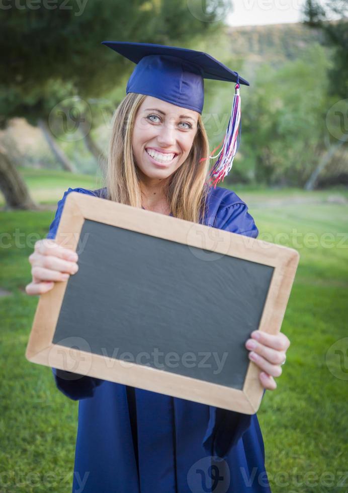Frau mit Diplom und leerer Tafel mit Mütze und Kleid foto
