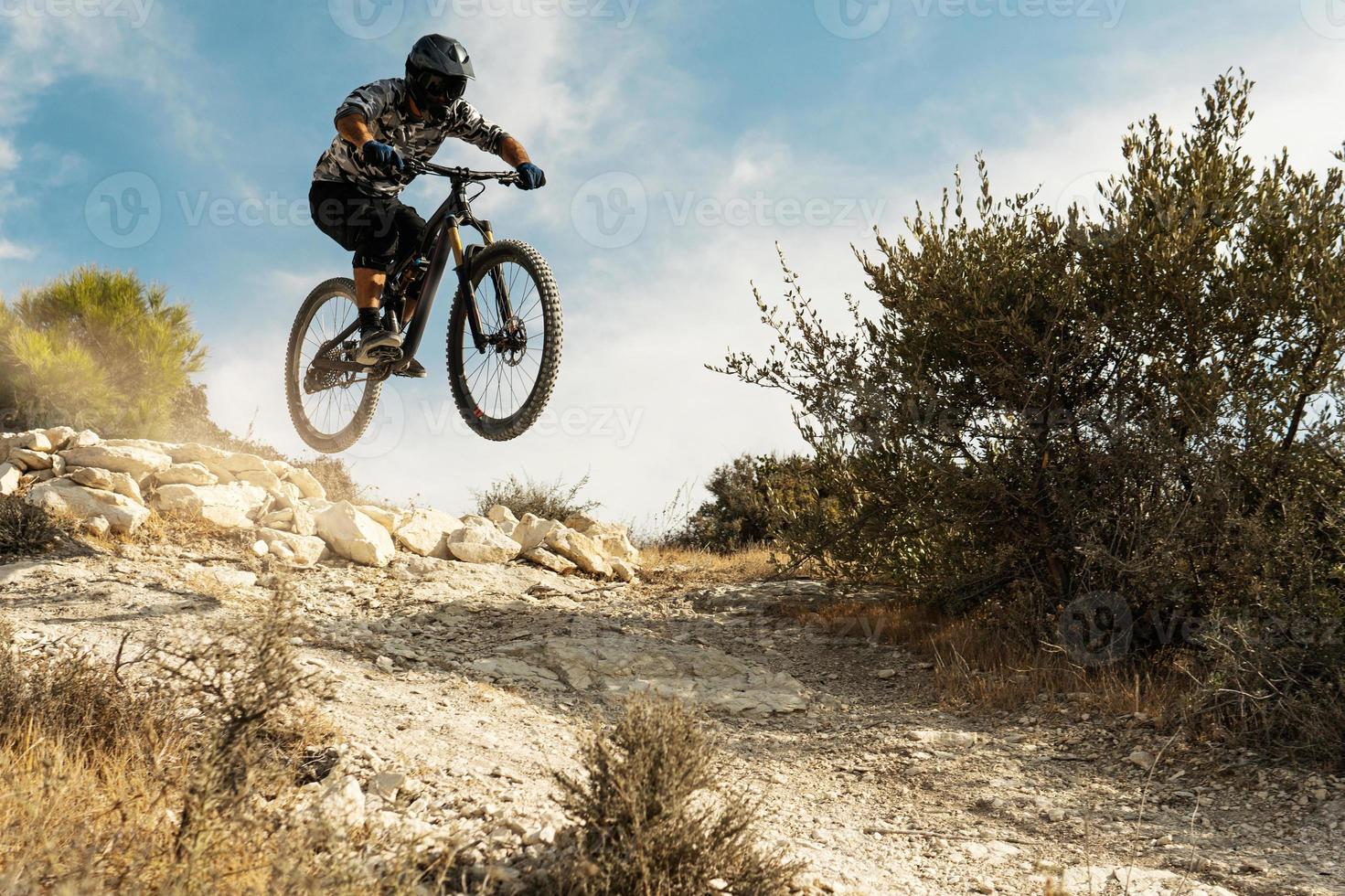 professioneller radfahrer, der während der bergabfahrt auf seinem fahrrad springt foto