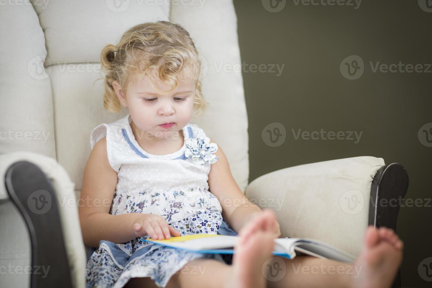 blondes blauäugiges kleines Mädchen, das ihr Buch liest foto