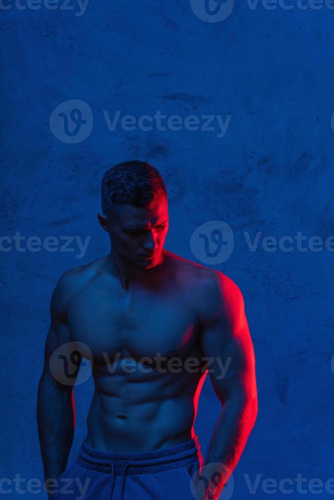 Bodybuilder posiert im bunten Neonlicht foto