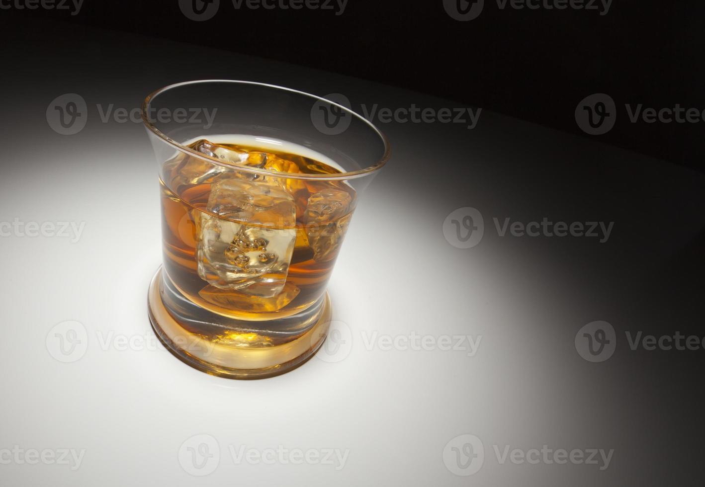 Glas Whiskey und Eis unter Scheinwerferlicht foto