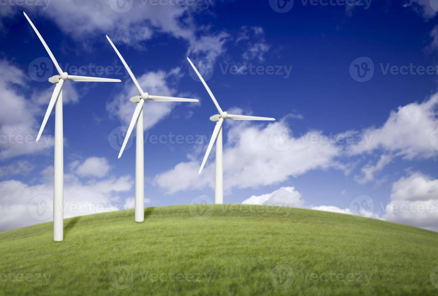 drei Windkraftanlagen über Wiese und blauem Himmel foto