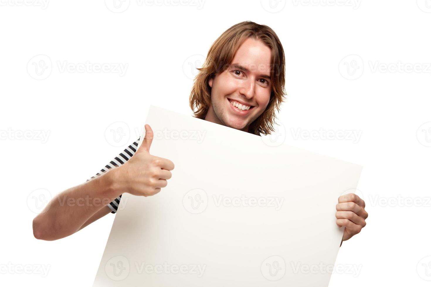lächelnder junger mann mit den daumen hoch, die leeres weißes schild halten foto