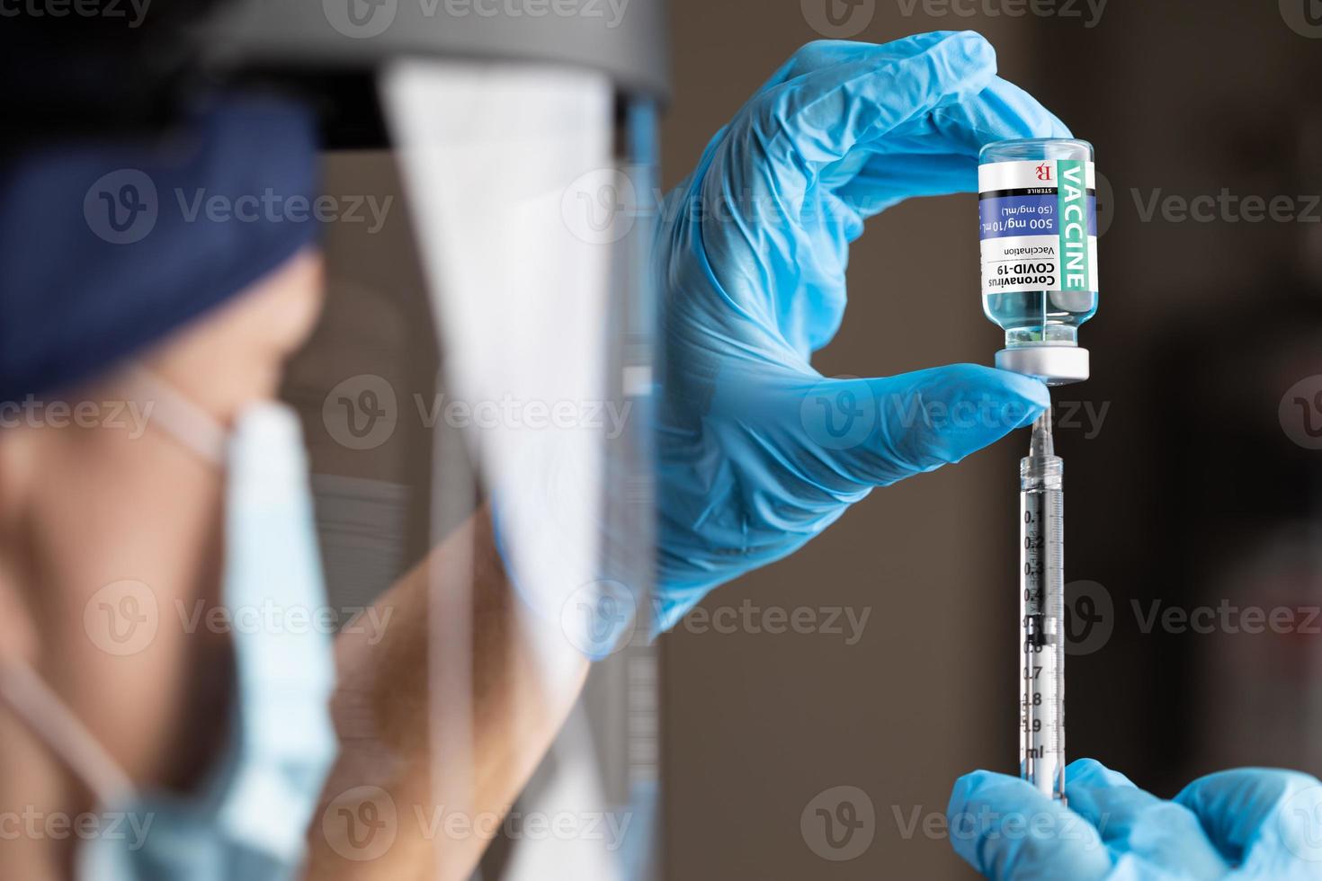 arzt oder krankenschwester, die chirurgische handschuhe tragen, die impffläschchen und medizinische spritze halten foto