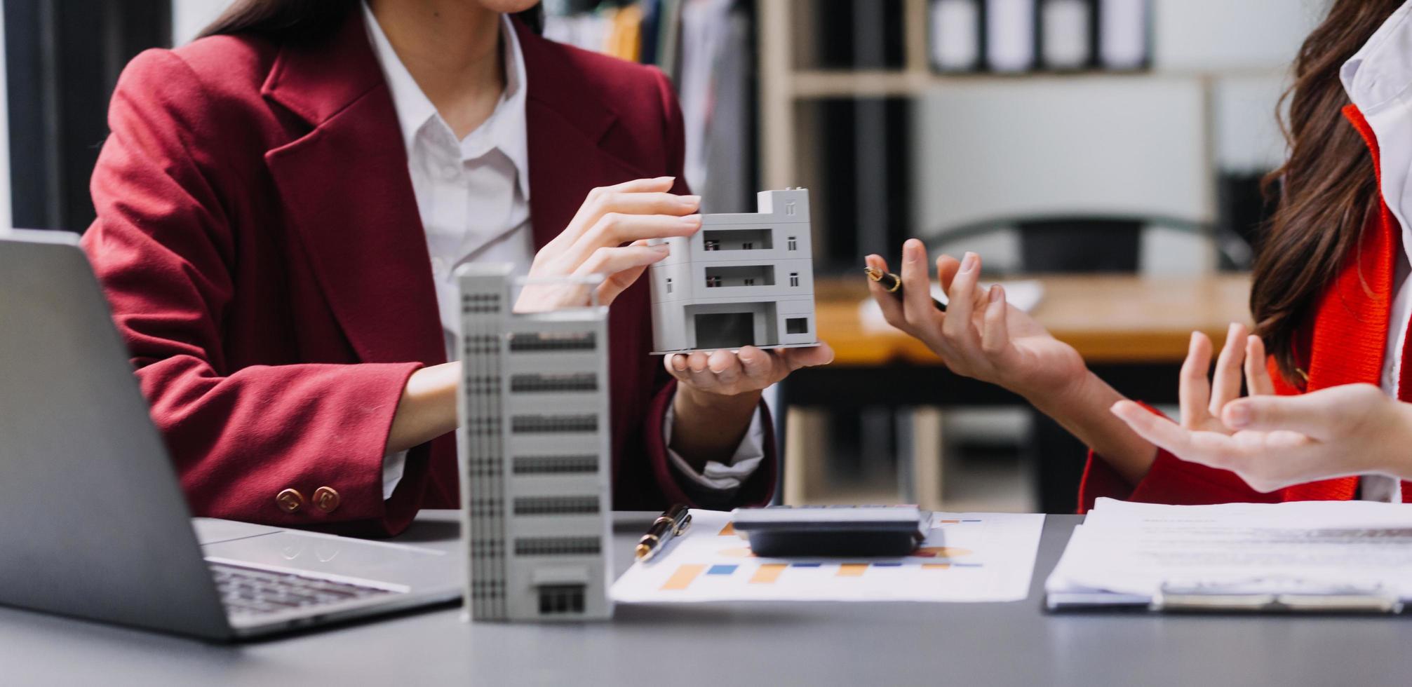 Diskussion mit einem Immobilienmakler, Hausmodell mit Makler und Kunde, der für den Kaufvertrag, den Abschluss einer Versicherung oder das Darlehen von Immobilien oder Grundstücken bespricht. foto