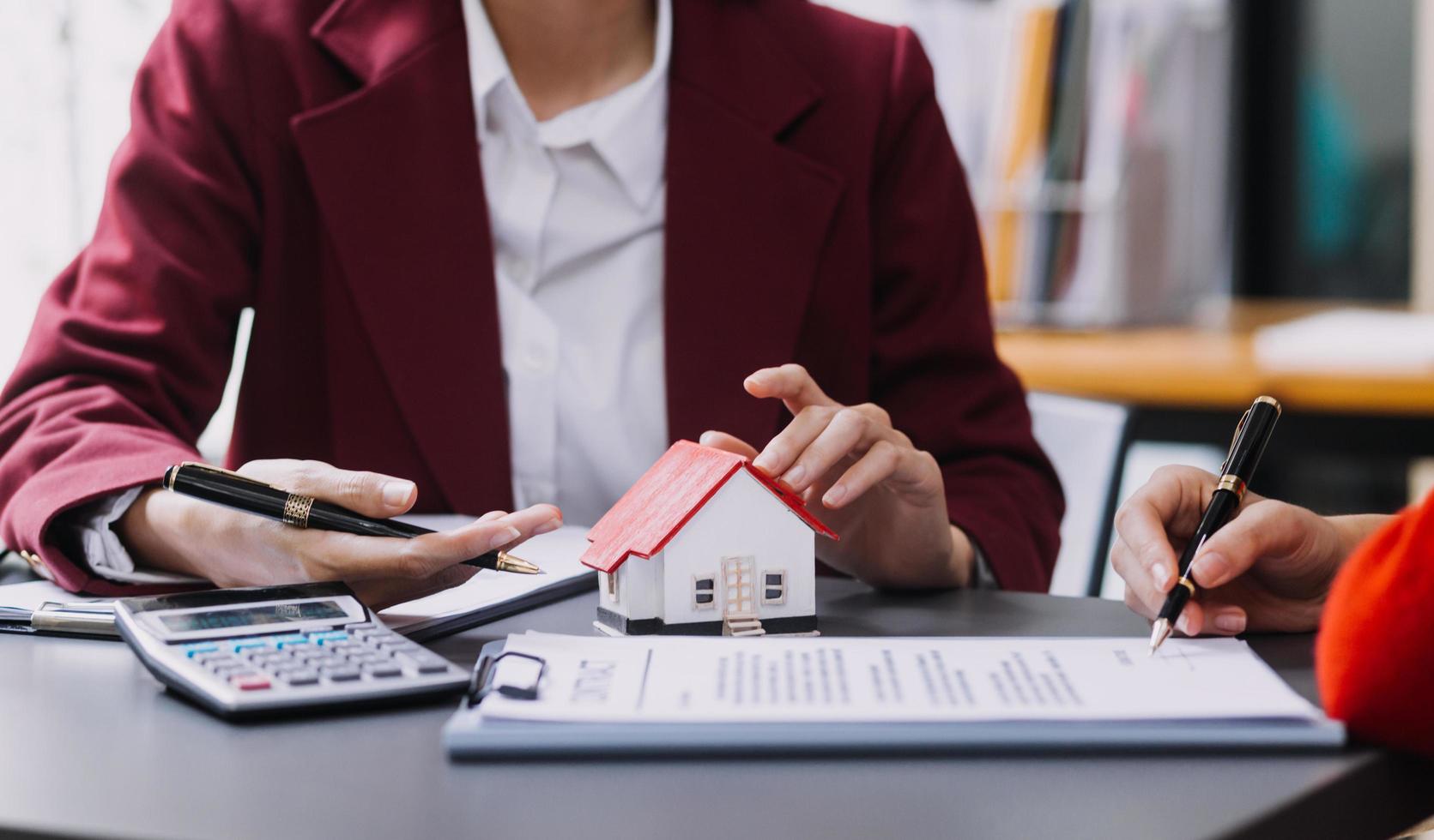 Diskussion mit einem Immobilienmakler, Hausmodell mit Makler und Kunde, der für den Kaufvertrag, den Abschluss einer Versicherung oder das Darlehen von Immobilien oder Grundstücken bespricht. foto