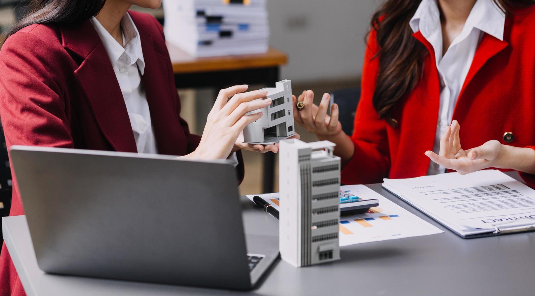 Diskussion mit einem Immobilienmakler, Hausmodell mit Makler und Kunde, der für den Kaufvertrag, den Abschluss einer Versicherung oder das Darlehen von Immobilien oder Grundstücken bespricht. foto