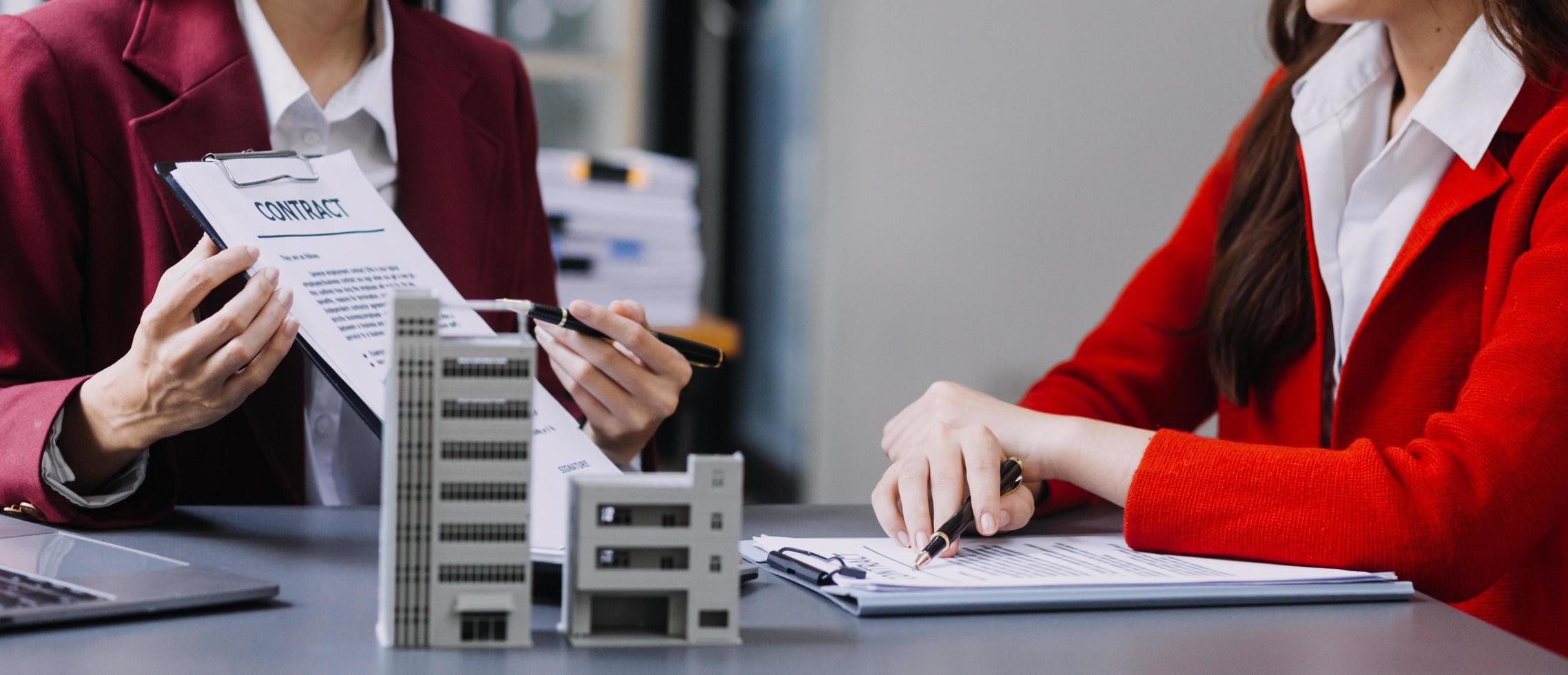 Diskussion mit einem Immobilienmakler, Hausmodell mit Makler und Kunde, der für den Kaufvertrag, den Abschluss einer Versicherung oder das Darlehen von Immobilien oder Grundstücken bespricht. foto