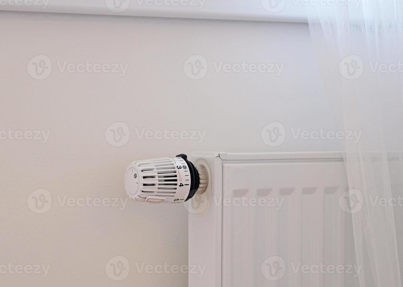 Banner mit Thermostat und Batterietemperaturregler. Heizkostenkonzept, Strompreiserhöhung. Temperaturregelventil. weiße heizung an der wand mit vorhang in moderner wohnung. foto