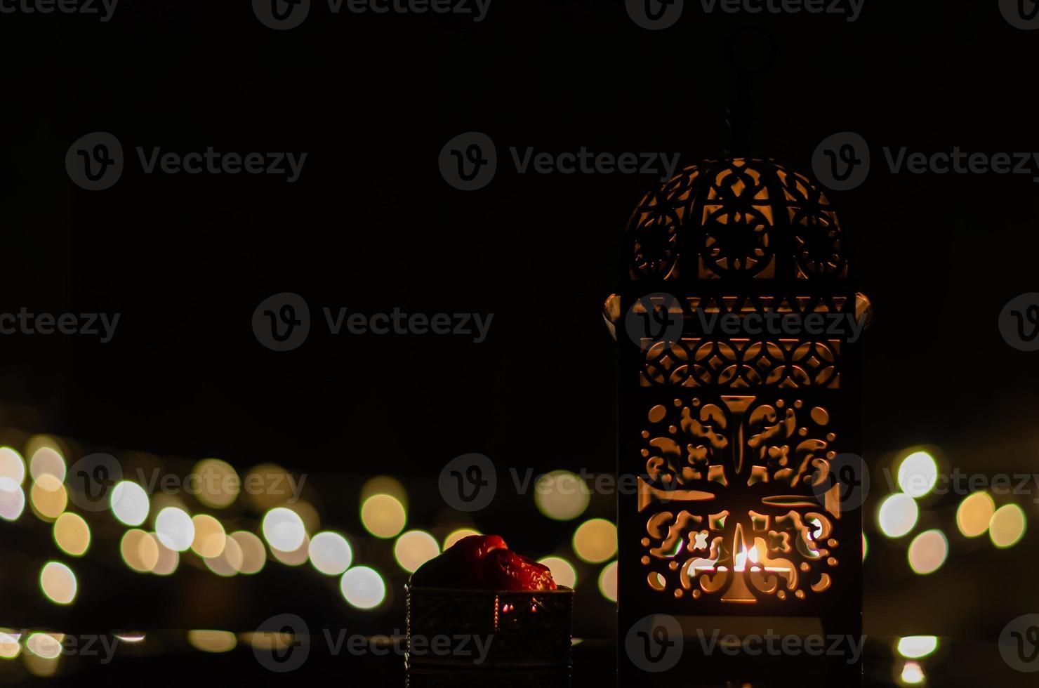 Laterne und Dattelfrüchte mit Bokeh-Licht im dunklen Hintergrund für das muslimische Fest des heiligen Monats Ramadan Kareem. foto