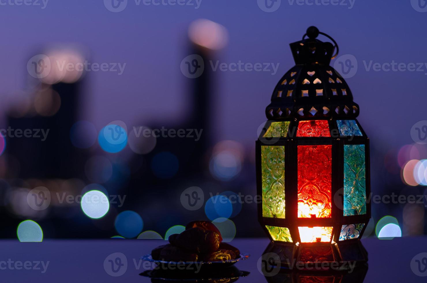 laterne und kleiner teller mit datteln obst mit nachthimmel und stadt bokeh heller hintergrund für das muslimische fest des heiligen monats ramadan kareem. foto