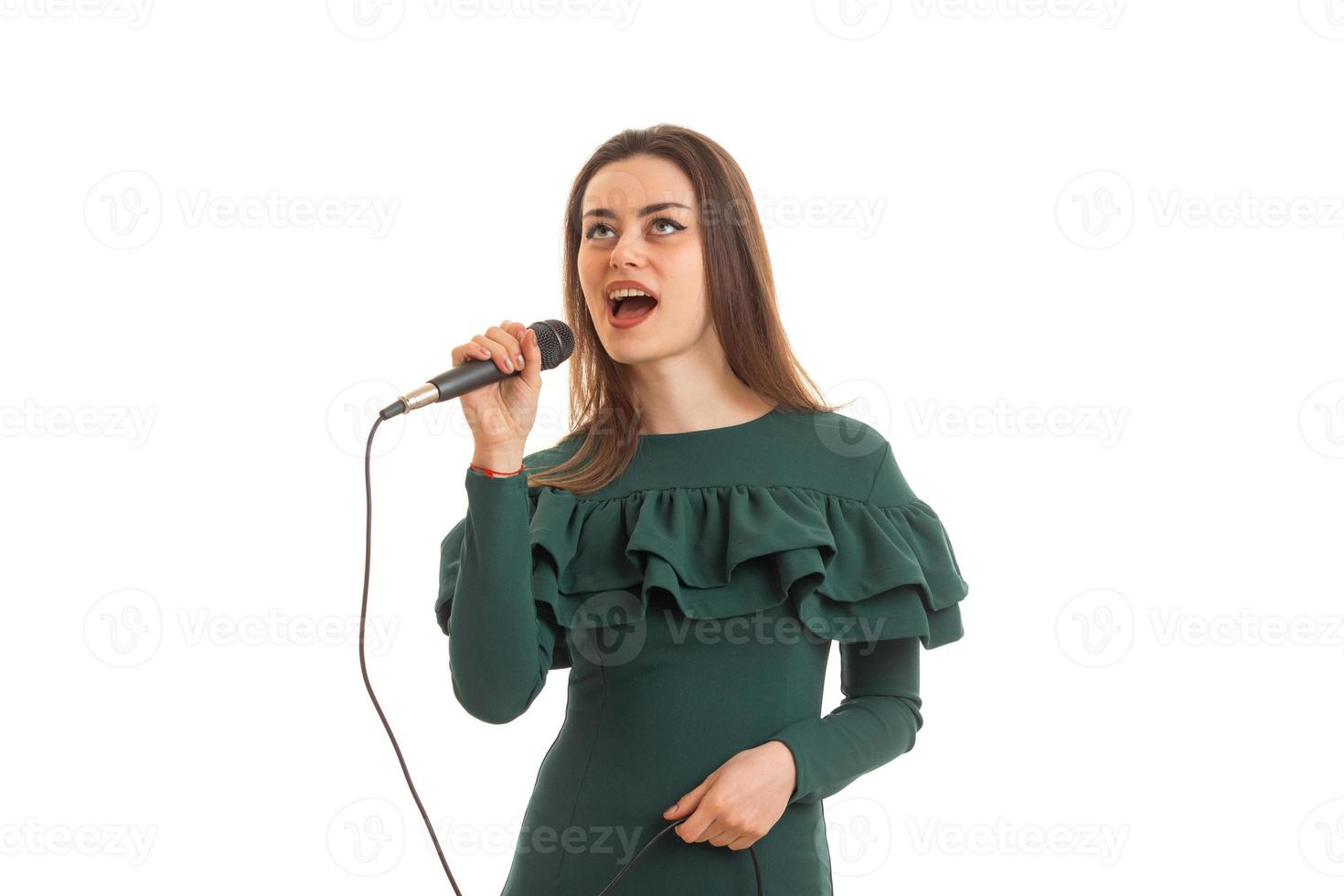 lustiges junges mädchen im grünen kleid, das karaoke singt foto