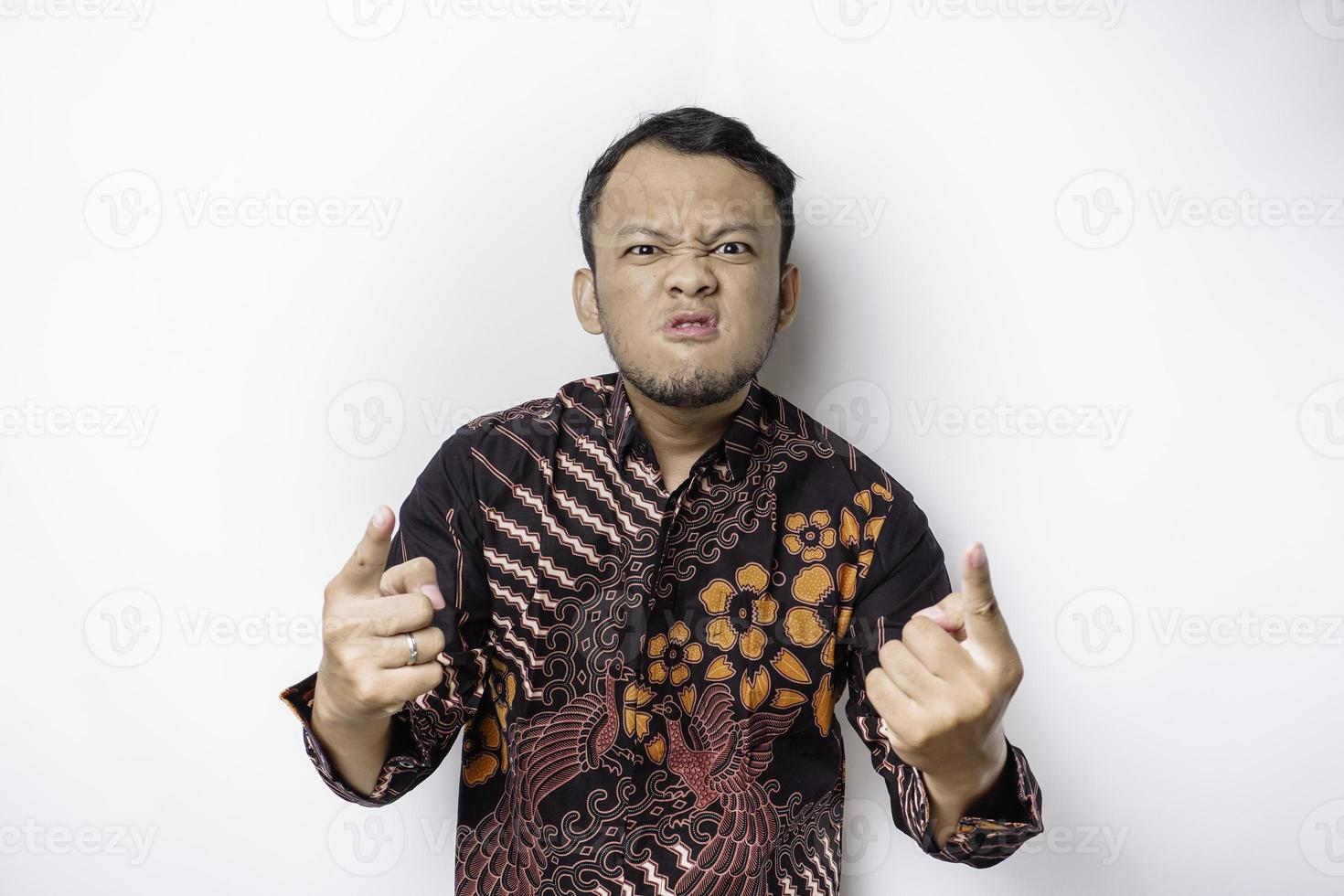 das wütende und wütende gesicht des asiatischen mannes im batikhemd lokalisierte weißen hintergrund. foto