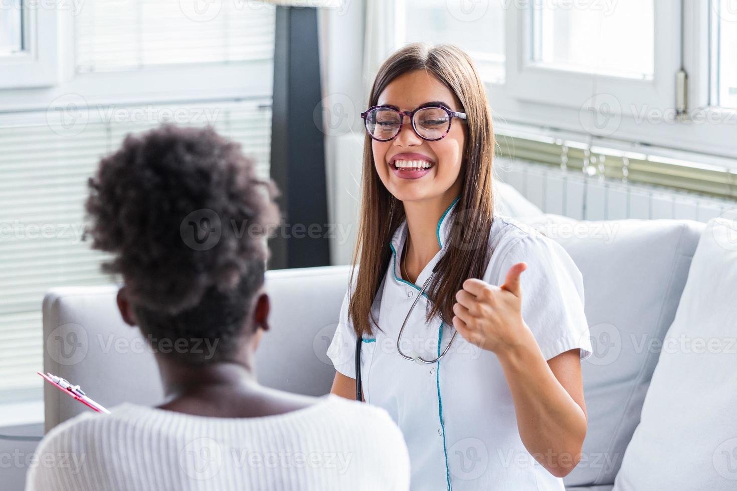 Arzt und Patient besprechen etwas, während sie am Tisch sitzen. medizin- und gesundheitskonzept. schöne junge Ärztin, die Daumen aufgibt foto