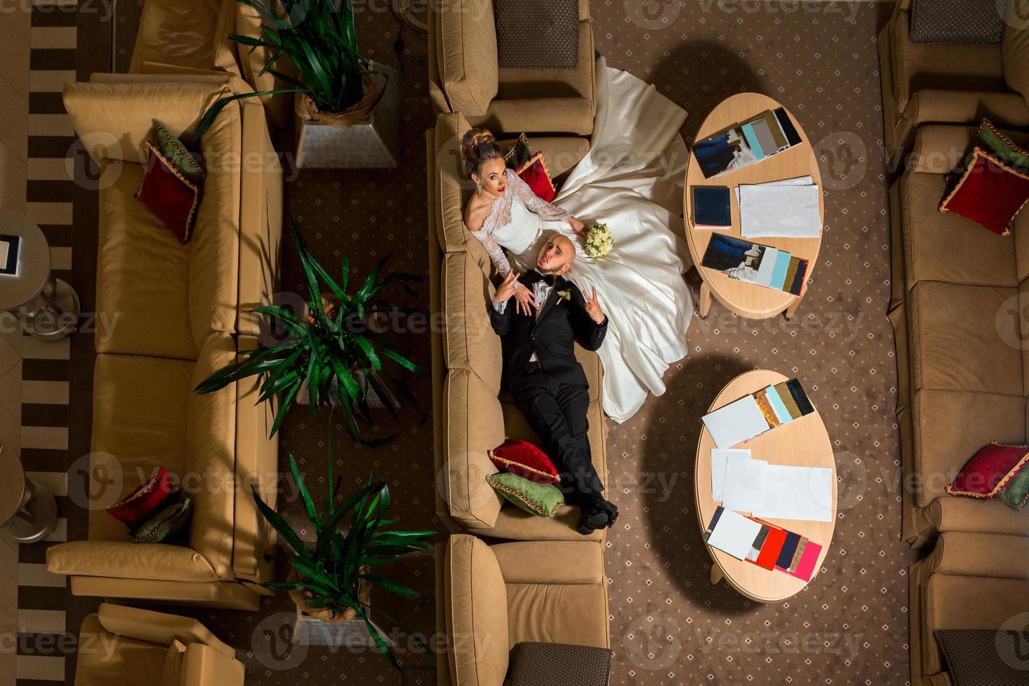 lustiges junges gerade verheiratetes paar, das auf einem sofa liegt foto