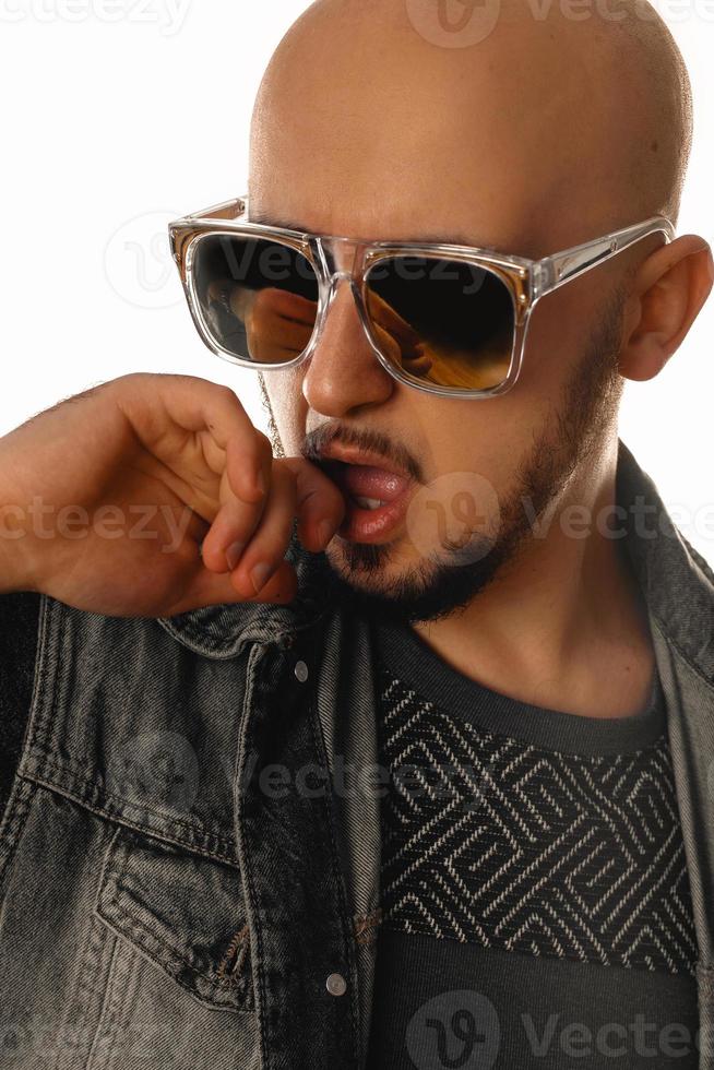 vertikales Porträt eines sexuellen jungen Macho-Mannes mit der Hand an seinem Mund in einer Sonnenbrille foto