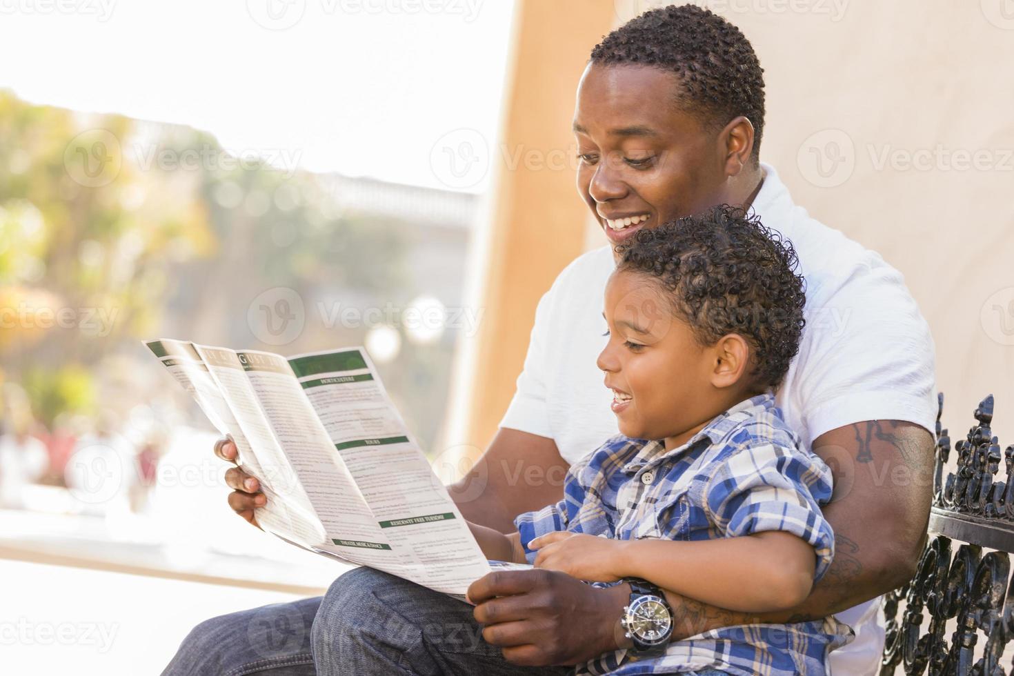 gemischter rassenvater und sohn lesen parkbroschüre draußen foto