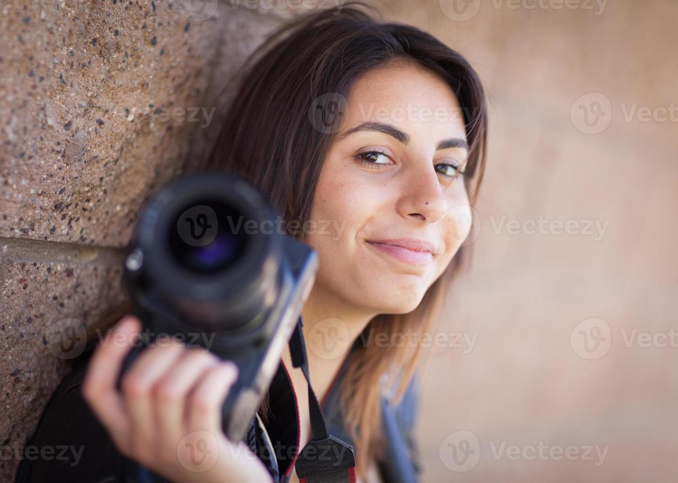 junger erwachsener ethnischer weiblicher fotograf gegen die wand, die kamera hält. foto