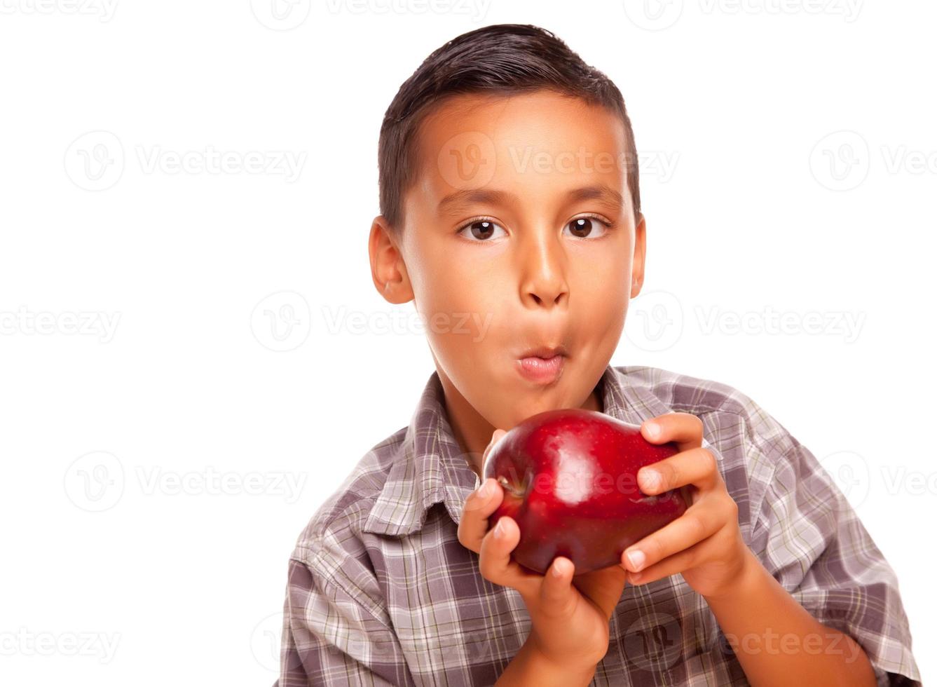 entzückender hispanischer Junge, der einen großen roten Apfel isst foto