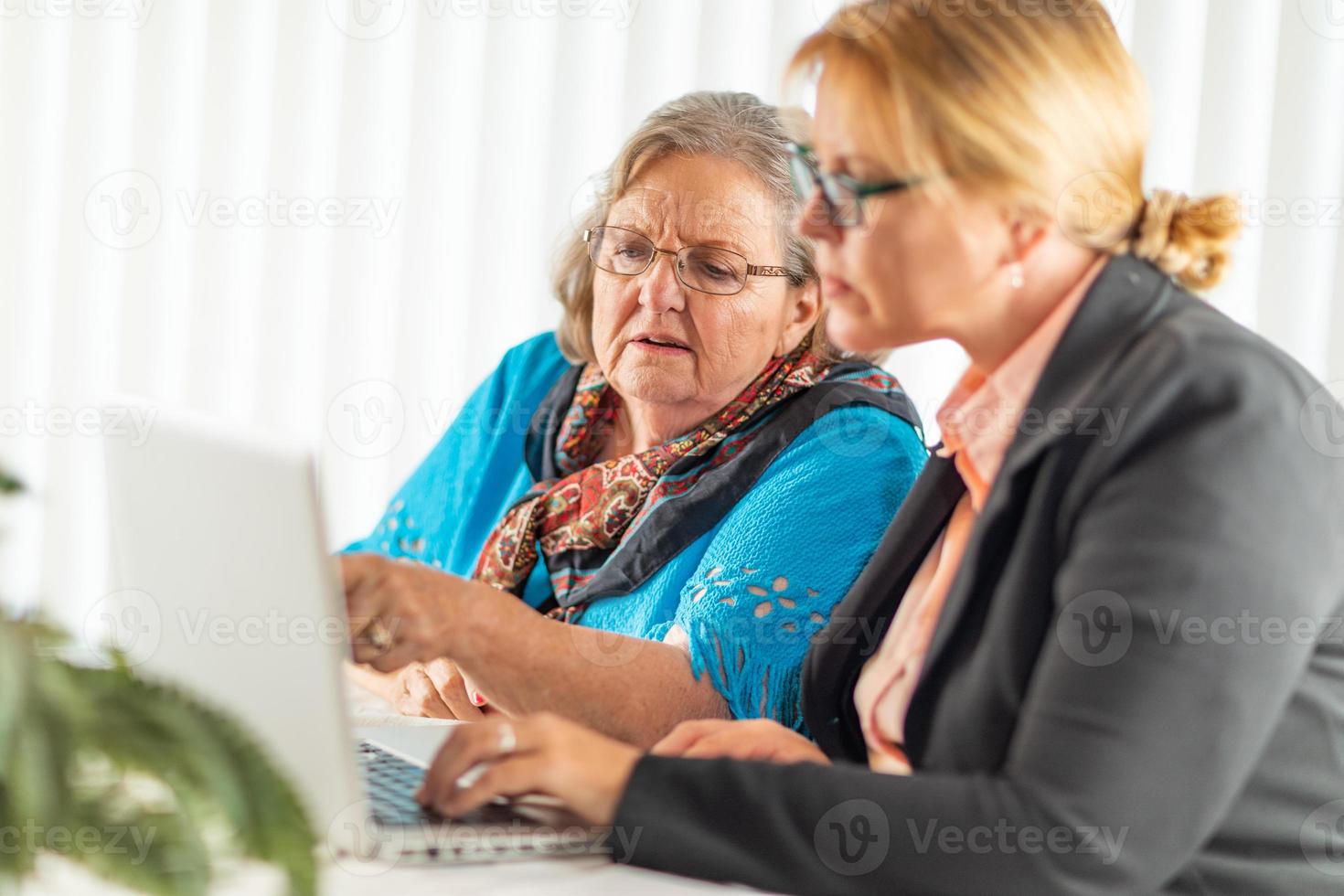 Frau, die älterer erwachsener Dame auf Laptop-Computer hilft foto