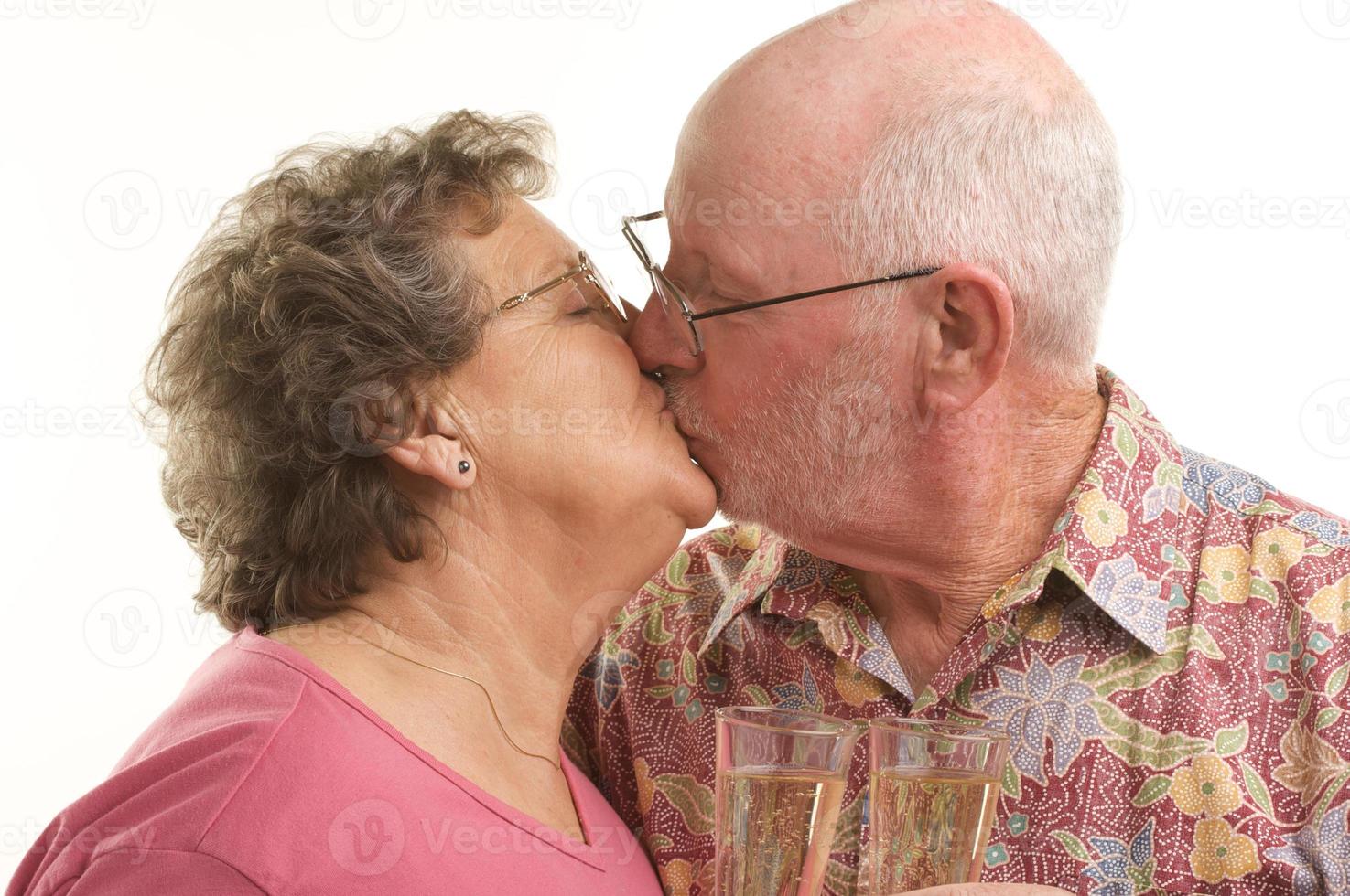 glückliches älteres paar, das mit champagnergläsern küsst foto