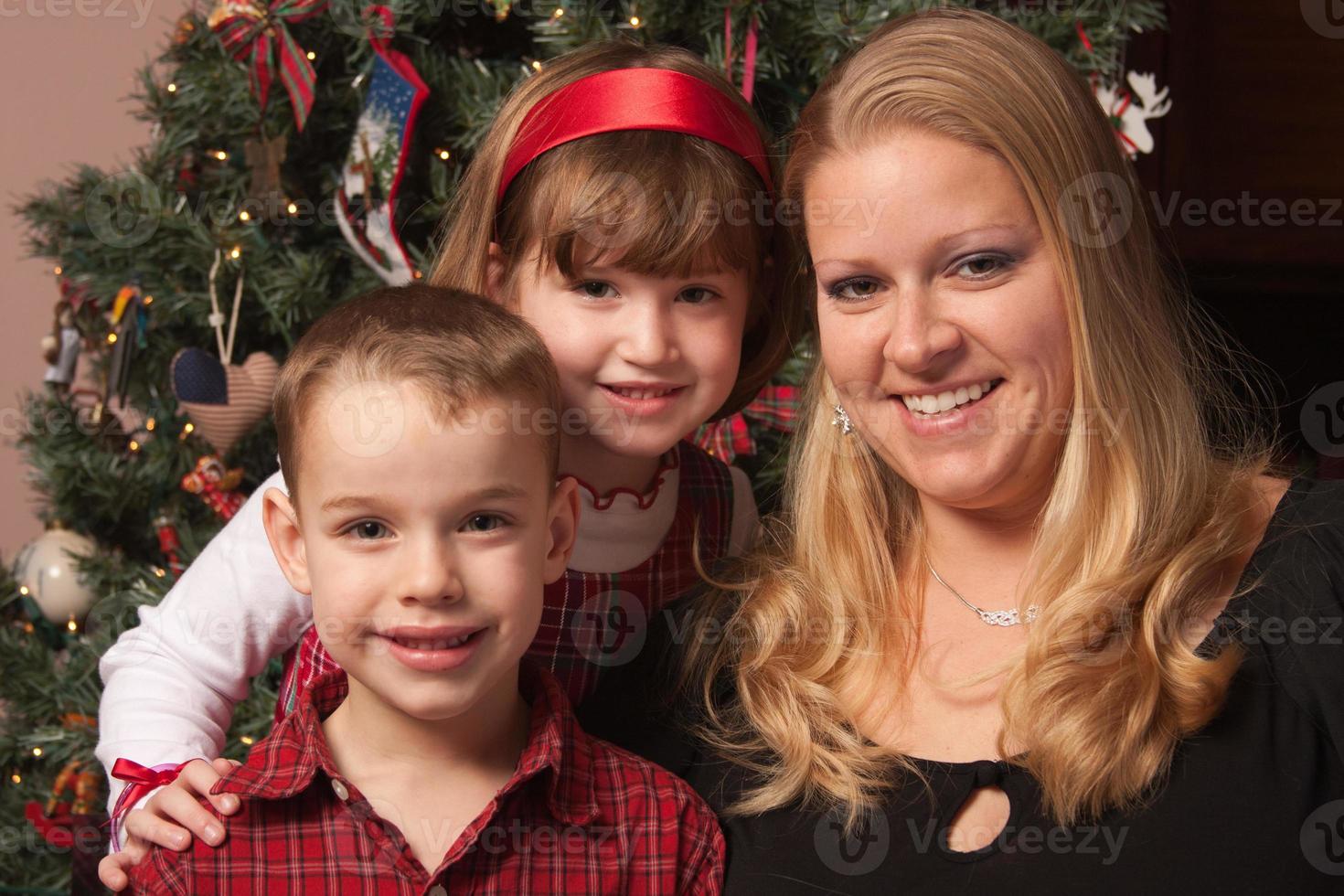 süße kinder und mutter posieren vor dem weihnachtsbaum foto