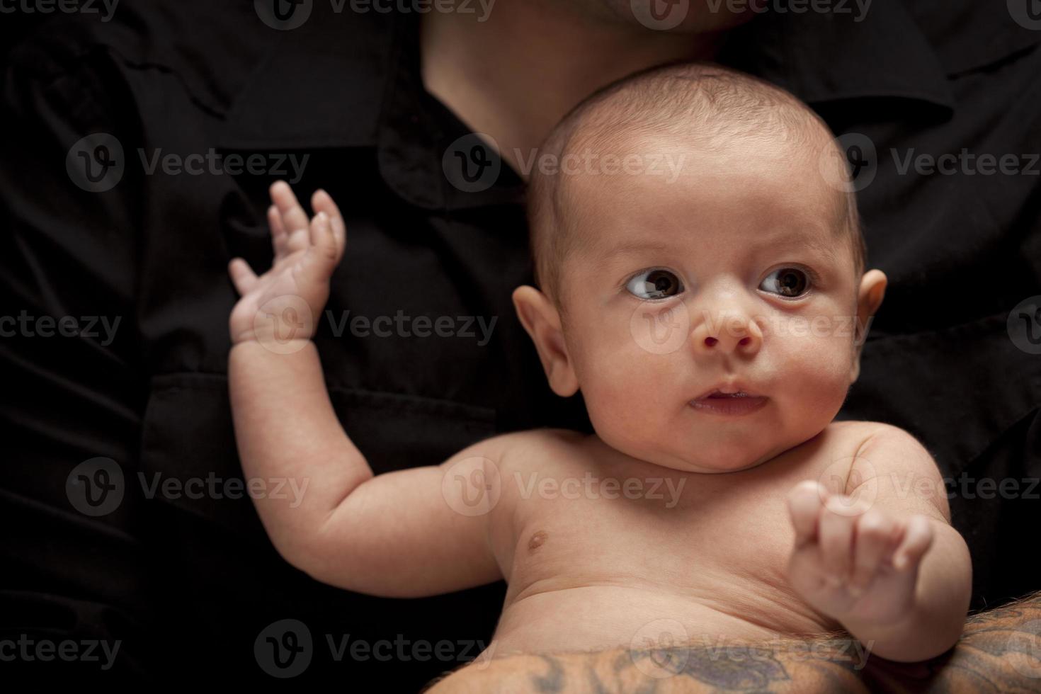 Junger Vater, der sein neugeborenes Baby der gemischten Rasse hält foto