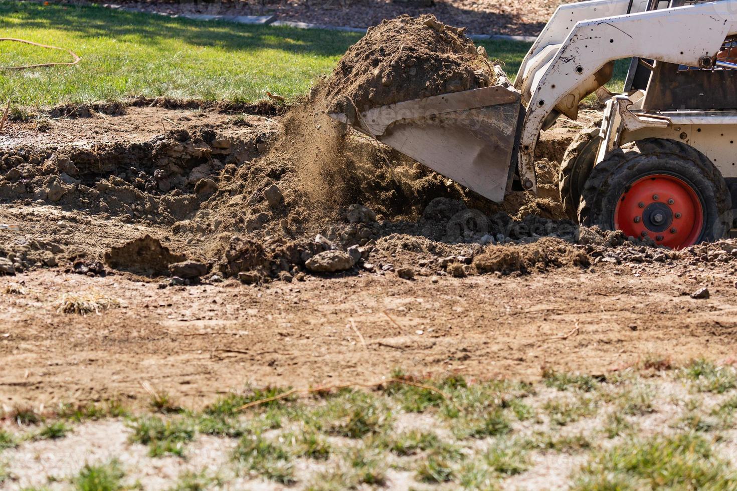 kleiner Bulldozer, der im Hof für die Poolinstallation gräbt foto