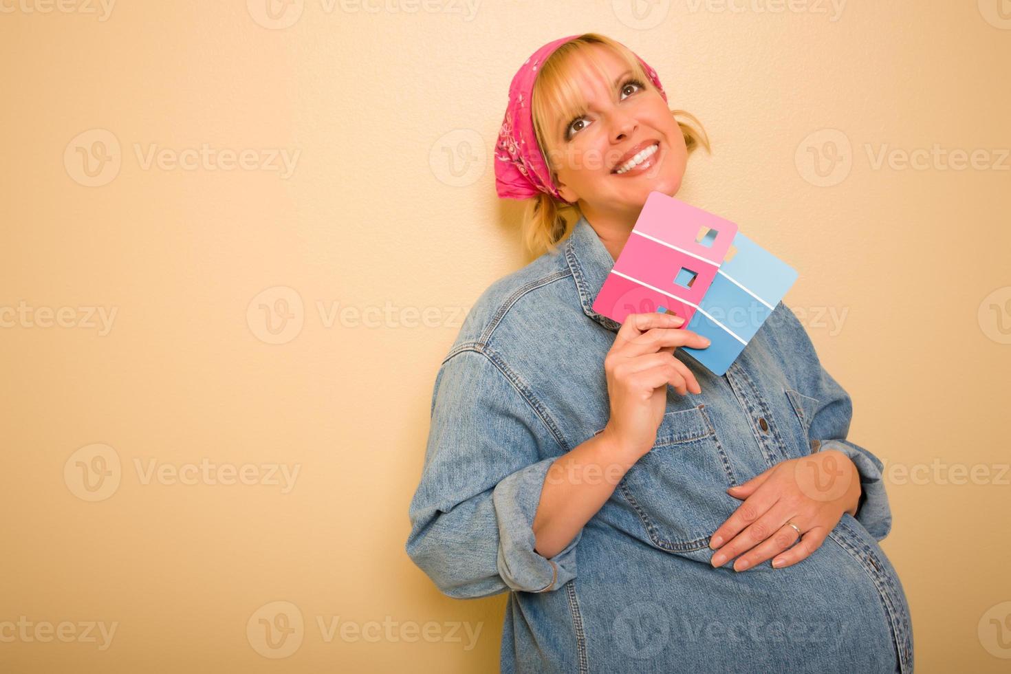 nachdenkliche schwangere frau, die rosa und blaue farbfelder hält foto