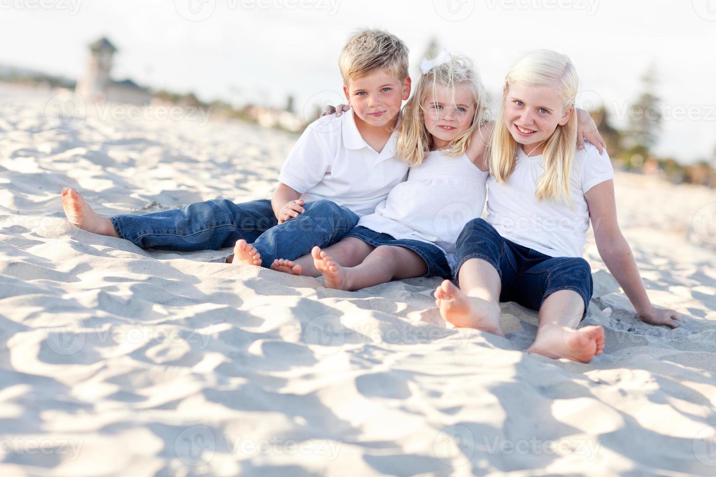 entzückende schwestern und bruder haben spaß am strand foto