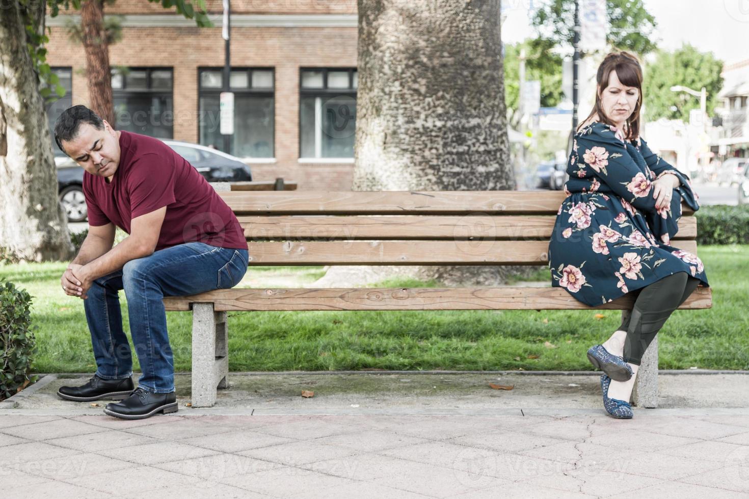 Unglückliches Mischlingspaar, das auf der Parkbank voneinander abgewandt sitzt foto