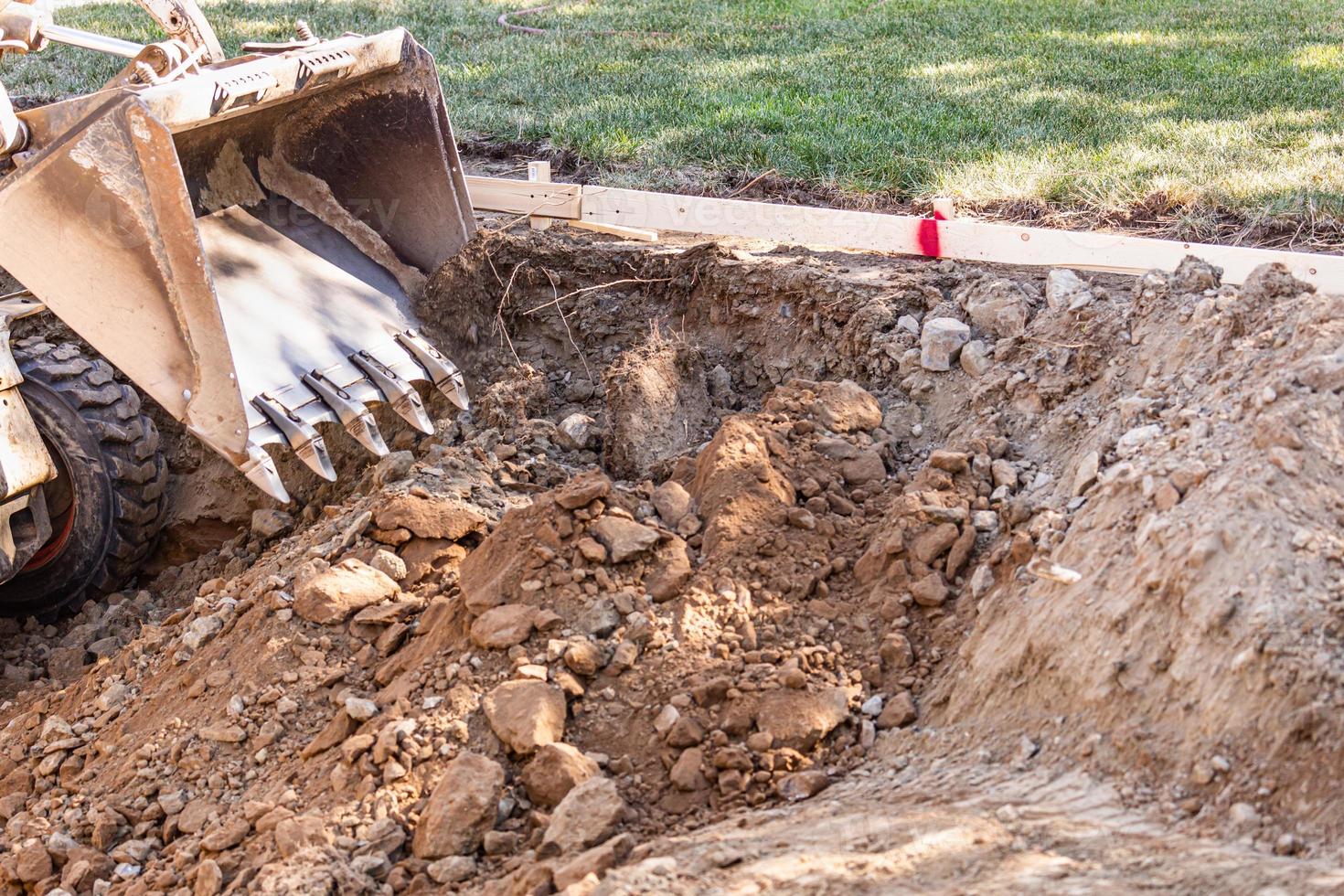 kleiner Bulldozer, der im Hof für die Poolinstallation gräbt foto