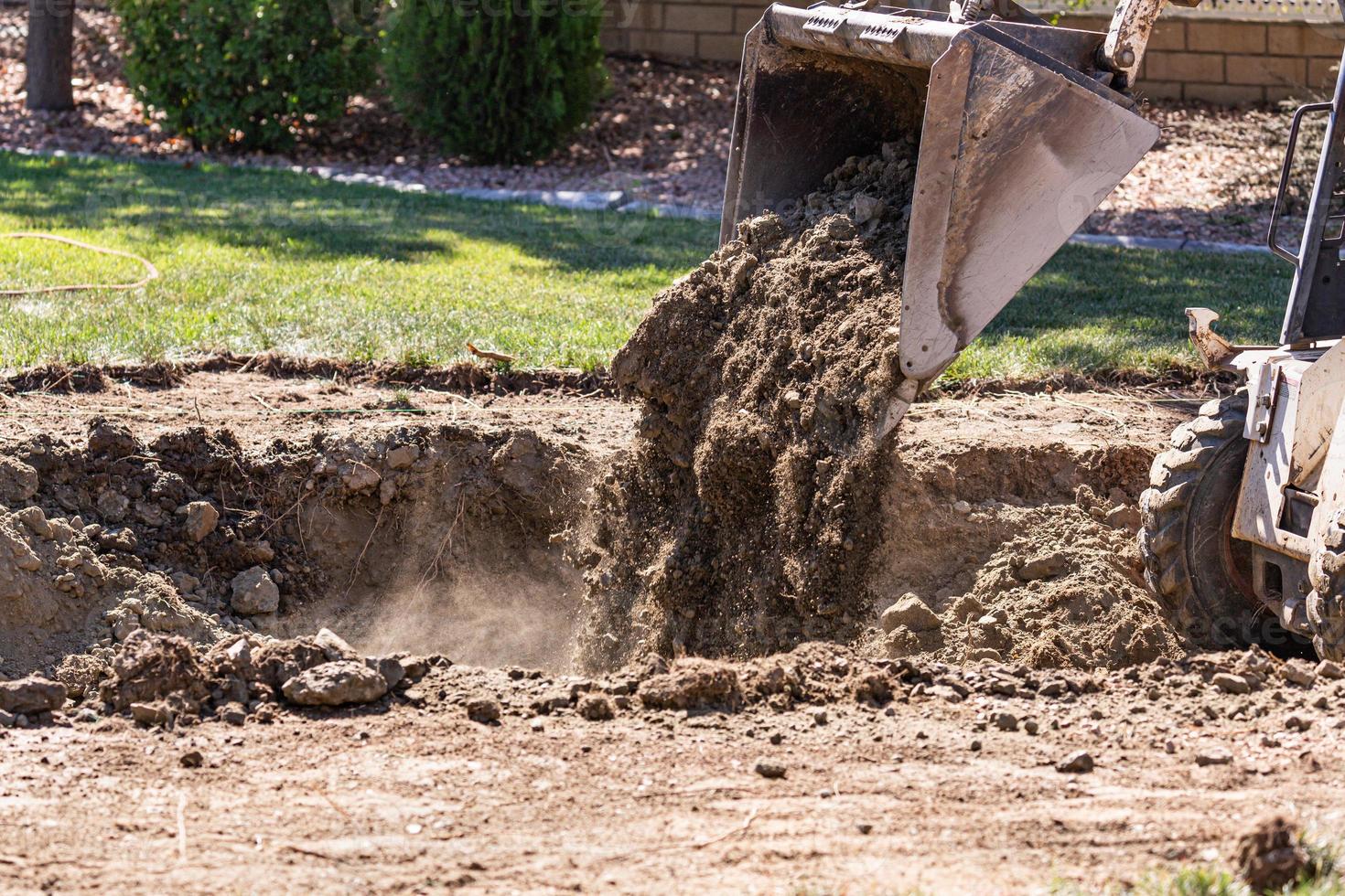 kleiner Bulldozer, der im Hof für die Poolinstallation gräbt foto