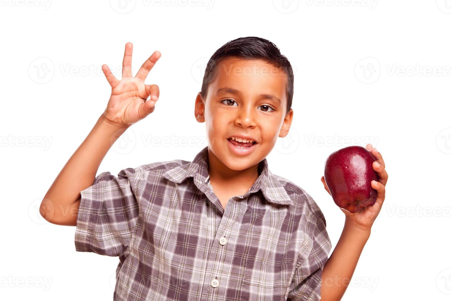 Entzückender hispanischer Junge mit Apfel und okayhandzeichen foto